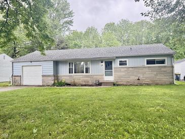 Charming single-story home with a stone facade and attached garage, surrounded by lush greenery at 3325 Canaday Dr, Anderson, IN 46013