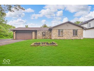 Charming stone facade home featuring a well-manicured lawn and attached two car garage at 8102 Sycamore Springs Trl, Indianapolis, IN 46239