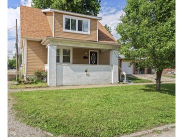 Charming two-story home with a covered front porch, landscaped lawn, and a detached garage in the back at 1720 Woodlawn Ave, Indianapolis, IN 46203