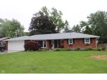 Charming brick home with attached garage, complemented by a lush green lawn and colorful landscaping at 1733 E 47Th St, Anderson, IN 46013