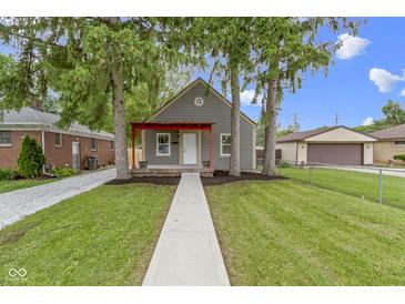 Charming home featuring a red porch and mature trees in a well-maintained yard at 2046 N Tibbs Ave, Indianapolis, IN 46222