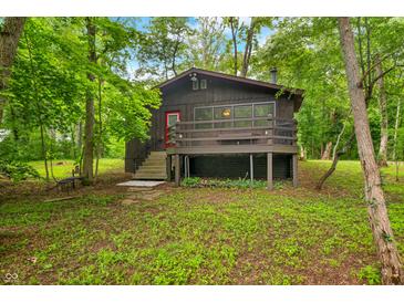 Charming home exterior with a red door, quaint porch, and nestled among mature trees at 2781 E Vandalia Rd, Flat Rock, IN 47234