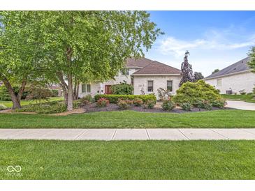 Charming brick home with a well-manicured lawn, mature trees, and vibrant flower beds showcasing curb appeal at 3655 Copperleaf Blvd, Greenwood, IN 46143