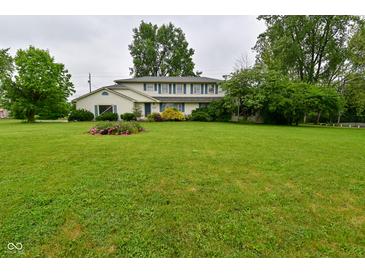 Traditional two-story home with a large front lawn and mature landscaping, including a flower bed at 5135 Moller Rd, Indianapolis, IN 46254