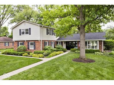 Charming two-story home featuring a mix of brick and siding, complemented by mature trees and manicured landscaping at 6115 E 65Th Pl, Indianapolis, IN 46220