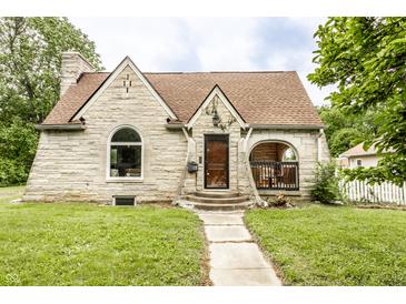 Charming stone home featuring a covered porch, arched window and a well-manicured lawn at 4435 E 38Th St, Indianapolis, IN 46218