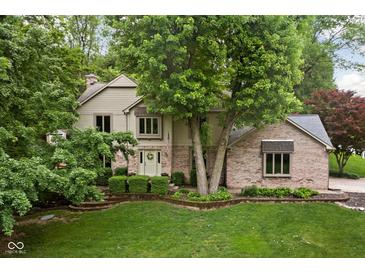 Charming two-story home with brick facade and a well-manicured front lawn nestled among mature trees at 5412 Green Hills Dr, Brownsburg, IN 46112