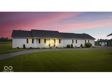 Charming home with a well-maintained lawn and a long driveway, set against a vibrant sunset backdrop at 9605 W 100 S, Jamestown, IN 46147