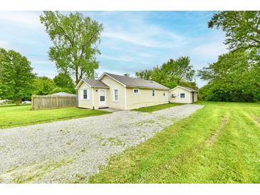 Charming single-story home with a gravel driveway and a detached garage, surrounded by lush greenery and mature trees at 1730 N Graham Ave, Indianapolis, IN 46218