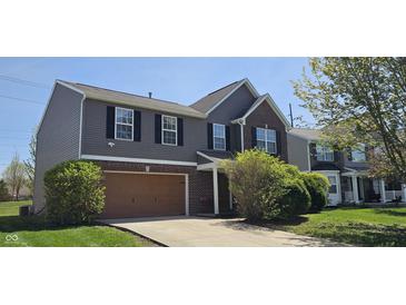 Lovely two-story home featuring a mix of siding and brick, a neat lawn, and an attached brown garage at 409 Spring Green Pl, Indianapolis, IN 46229