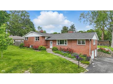 Charming red brick home featuring manicured lawn, colorful flower beds, and inviting curb appeal at 4614 Thornleigh Dr, Indianapolis, IN 46226