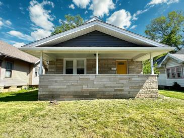 Charming single-story home featuring stone accents, covered porch, and a bright yellow front door at 4814 E New York St, Indianapolis, IN 46201