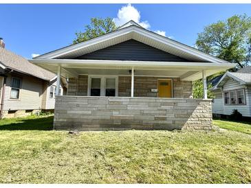 Charming home featuring a stone front porch, yellow front door, and inviting curb appeal at 4814 E New York St, Indianapolis, IN 46201