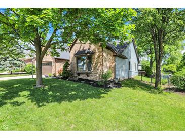 Charming brick home featuring manicured lawn and mature shade trees in a serene, suburban setting at 10560 Lighthouse Way, Indianapolis, IN 46256