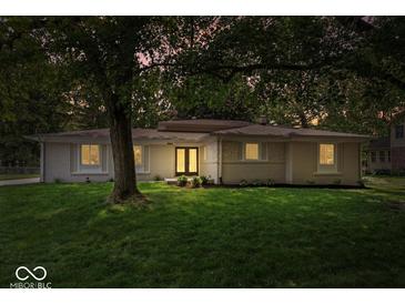 Charming single-story home featuring a lush green lawn and beautiful mature trees at 11123 Haverstick Rd, Carmel, IN 46033