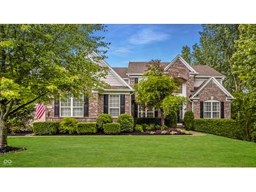 Charming brick home featuring manicured lawn, beautiful landscaping, and a welcoming facade at 11552 Buckskin Dr, Zionsville, IN 46077