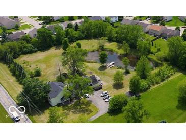 An aerial view shows a charming home with a pond, a small pier, and lush greenery surrounding the property at 6336 N Carroll Rd, Indianapolis, IN 46235