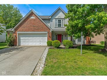 Charming two-story home features a well-manicured lawn, red door and attached two-car garage at 8376 Glen Highlands Dr, Indianapolis, IN 46236