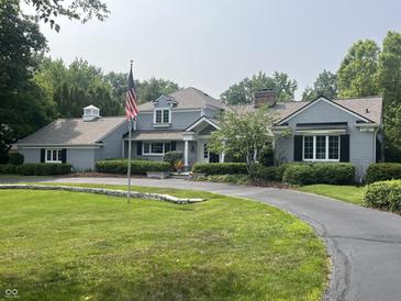 Stately gray home with an American flag, circular driveway, and well-manicured lawn and landscaping at 9510 Copley Dr, Indianapolis, IN 46260