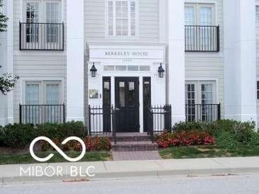 Inviting building entrance featuring well-maintained landscaping, black iron railings, and a charming overhead sign at 12860 University Cres # 1B, Carmel, IN 46032