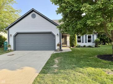 Charming single-Gathering home featuring a gray garage door, lush lawn, and mature trees at 17841 Grassy Knoll Dr, Westfield, IN 46074