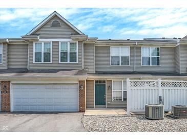Inviting townhome features a one-car garage, green door, and charming white picket fence, creating a welcoming curb appeal at 2306 Brightwell Pl, Indianapolis, IN 46260