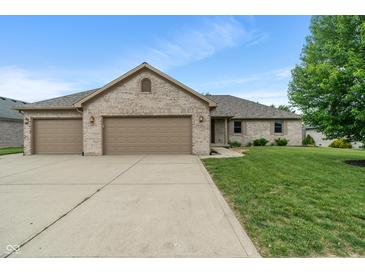 Charming brick home with a three-car garage and a well-manicured lawn on a sunny day at 2422 Oak Dr, Clayton, IN 46118