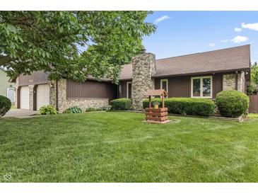 Charming home featuring a stone chimney, well-manicured lawn, and attractive landscaping at 7426 N Carroll Rd, Indianapolis, IN 46236