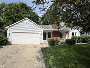 Charming home featuring a lush front lawn, attached garage, and brick chimney at 912 Delray Dr, Indianapolis, IN 46241