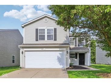 Charming two-story home featuring an attached garage and classic curb appeal with a tree at 1936 Southernwood Ln, Indianapolis, IN 46231