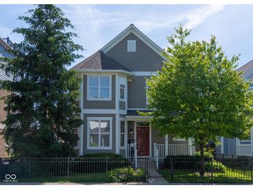 Charming two-story home with a red door, black fence, and mature trees in a well-maintained yard at 2445 N Delaware St, Indianapolis, IN 46205