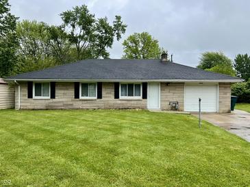 Charming one-story home with a well-maintained lawn, stone exterior, and attached garage at 4004 N Ball Ave, Muncie, IN 47304