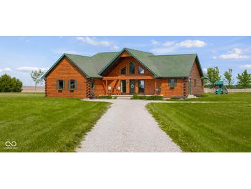 A charming log home featuring a well-maintained lawn and a quaint gravel driveway at 8981 N 325 E, Columbus, IN 47203