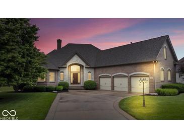 Stunning brick home boasts a three-car garage, mature landscaping, and a welcoming stone entrance at 14711 Macduff Dr, Noblesville, IN 46062