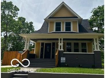 Charming yellow two-story home featuring a covered front porch and manicured lawn at 2936 Guilford Ave, Indianapolis, IN 46205