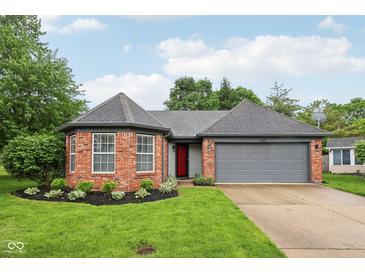 Charming brick home featuring an attached garage and a well-manicured lawn, with a red front door at 7061 Woodgate Cir, Fishers, IN 46038