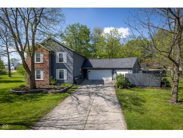 Charming home featuring a long driveway and a two-car garage, framed by mature trees and a well-maintained lawn at 1052 Barley Cir, Carmel, IN 46032