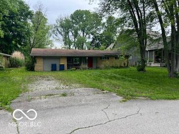 Modest single-story home with a red front door, attached garage and an unkempt front yard at 130 Napanee Dr, Carmel, IN 46032