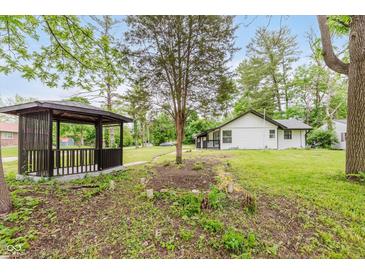 Backyard featuring a cozy gazebo, lush trees, and green grass surrounding the home at 233 N Devon Ave, Indianapolis, IN 46219