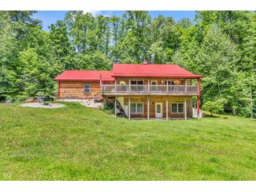 Beautiful log home with a red metal roof and a wraparound porch, surrounded by lush greenery at 2780 W Grizzly Trl, Martinsville, IN 46151