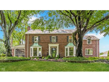 Charming brick two-story home with a manicured lawn, mature trees, and beautiful copper bay windows at 5165 E Pleasant Run Pkwy S Dr, Indianapolis, IN 46219