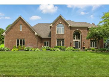 Charming two-story brick home with an arched entry, manicured lawn, and mature landscaping at 5419 Cayman Dr, Carmel, IN 46033