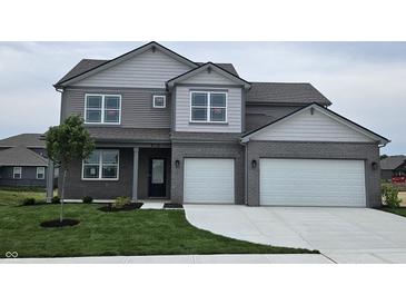 Charming two-story home featuring a two-car garage, gray brick, lush lawn and manicured landscaping at 6049 Madera Dr, Whitestown, IN 46075