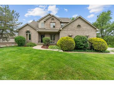 Charming two-story brick home with a lush green lawn and manicured landscaping at 7141 Ember Ct, Indianapolis, IN 46236