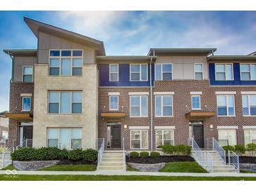 Modern townhouse featuring a combination of brick and stone facade, complemented by well-manicured landscaping at 13050 Grand Vue Dr, Carmel, IN 46032