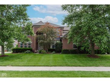 Beautiful brick home with a manicured lawn and mature trees providing shade and curb appeal at 13693 Cunningham Dr, Carmel, IN 46074