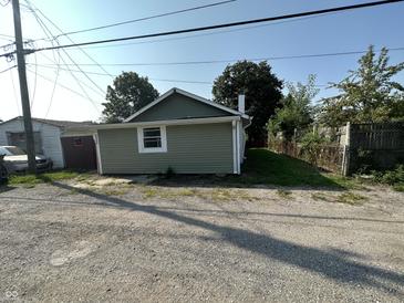 View of house from driveway with green siding and a white chimney on a bright day at 2310 E Raymond St, Indianapolis, IN 46203