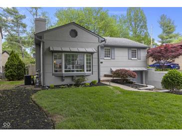 Charming two-story home featuring manicured front yard with healthy lawn and mature tree at 5543 N Pennsylvania N St, Indianapolis, IN 46220