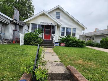 Charming two-story home with a well-manicured lawn, sidewalk, and decorative shrubs at 621 E 31St St, Anderson, IN 46016