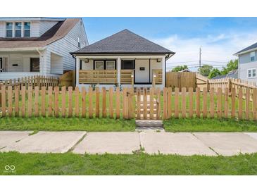 Charming home featuring a cozy front porch and a well-maintained lawn with a decorative wooden fence at 2909 E Michigan St, Indianapolis, IN 46201